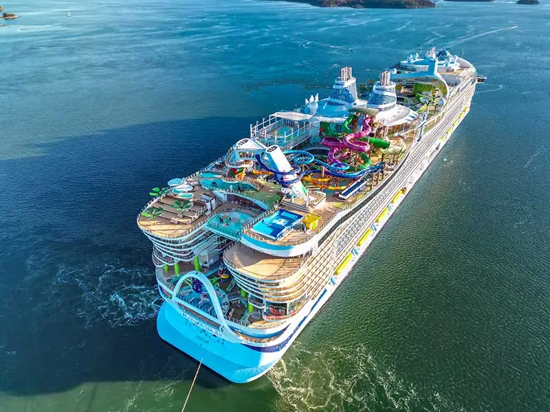 Icon of the Seas, the world's largest luxury cruise ship, sailing across the ocean during sunset with its modern design and illuminated decks.