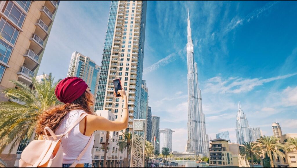 Dubai content creator filming videos with smartphone in front of the Dubai skyline.